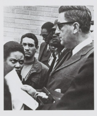 Photograph of several Black NIU students presenting President Smith with their list of demands. 